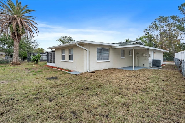 rear view of property featuring cooling unit, a patio area, a lawn, and a sunroom