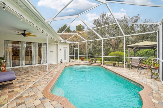 view of swimming pool featuring glass enclosure, a patio area, a gazebo, and ceiling fan