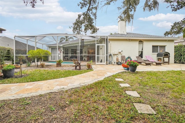 back of house featuring glass enclosure, a patio, and a lawn