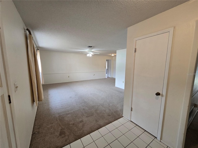 empty room featuring ceiling fan, light colored carpet, and a textured ceiling