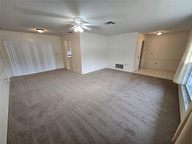 carpeted spare room with ceiling fan and a textured ceiling