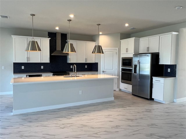 kitchen featuring marble finish floor, stainless steel appliances, wall chimney range hood, and a sink