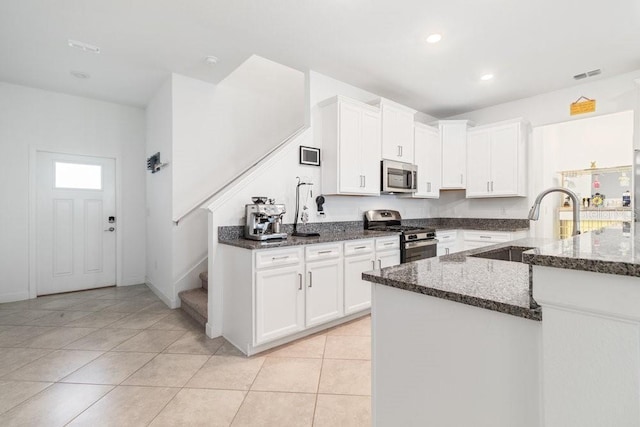 kitchen featuring sink, dark stone countertops, appliances with stainless steel finishes, kitchen peninsula, and white cabinets