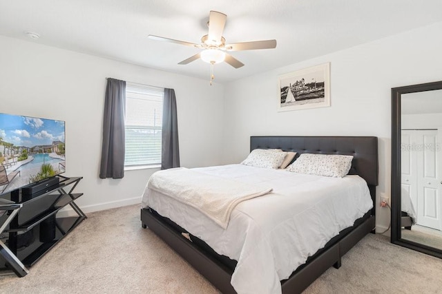 bedroom with ceiling fan, light carpet, and a closet