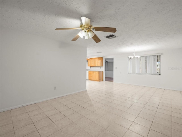 spare room featuring ceiling fan with notable chandelier, a textured ceiling, and light tile patterned flooring