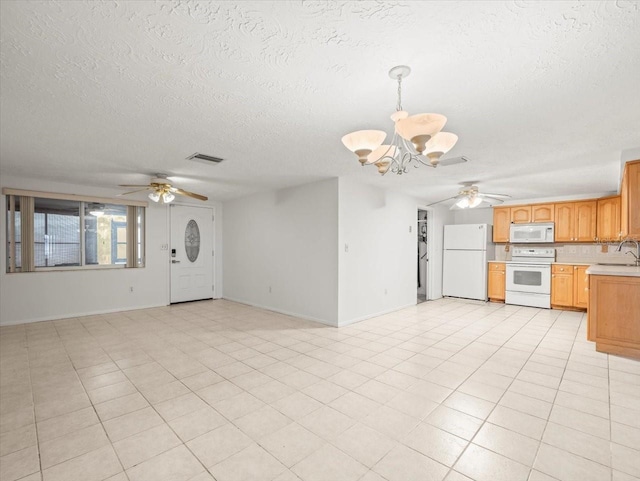 unfurnished living room with sink, ceiling fan with notable chandelier, light tile patterned floors, and a textured ceiling