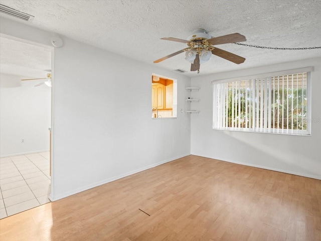 spare room with light wood-type flooring, ceiling fan, and a textured ceiling