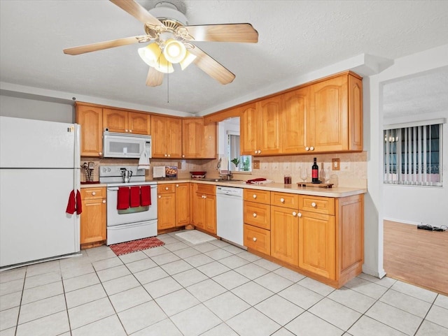 kitchen with light tile patterned flooring, a textured ceiling, ceiling fan, white appliances, and decorative backsplash