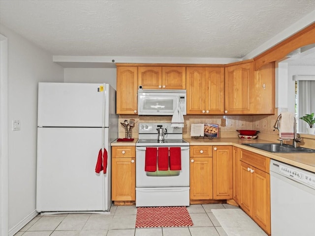 kitchen with sink, white appliances, light tile patterned floors, tasteful backsplash, and a textured ceiling