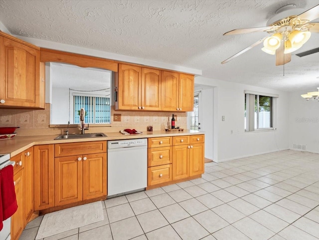 kitchen with sink, white dishwasher, tasteful backsplash, a textured ceiling, and light tile patterned flooring