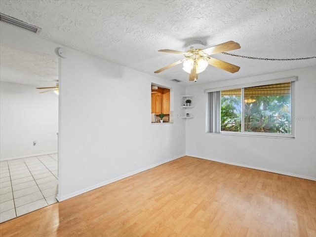 spare room with ceiling fan, a textured ceiling, and light wood-type flooring