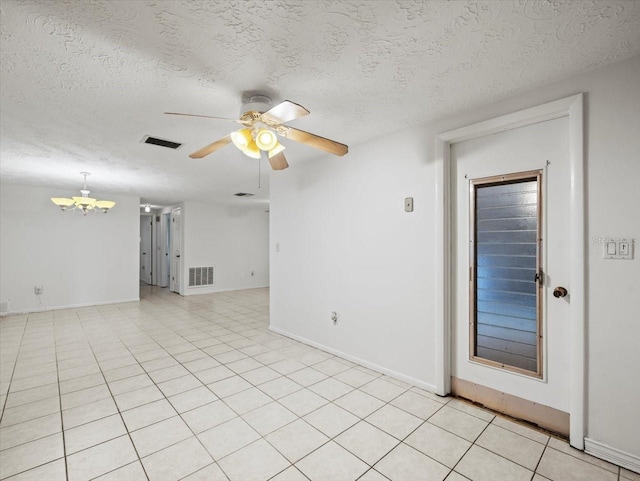 tiled empty room featuring ceiling fan with notable chandelier and a textured ceiling