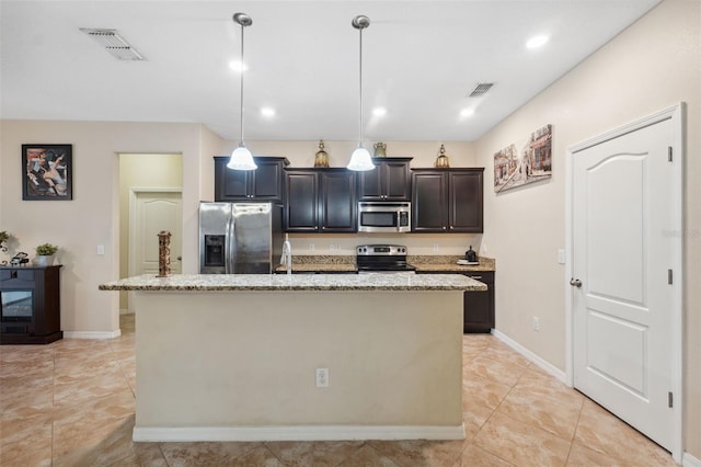 kitchen with light stone countertops, appliances with stainless steel finishes, a kitchen island with sink, and pendant lighting