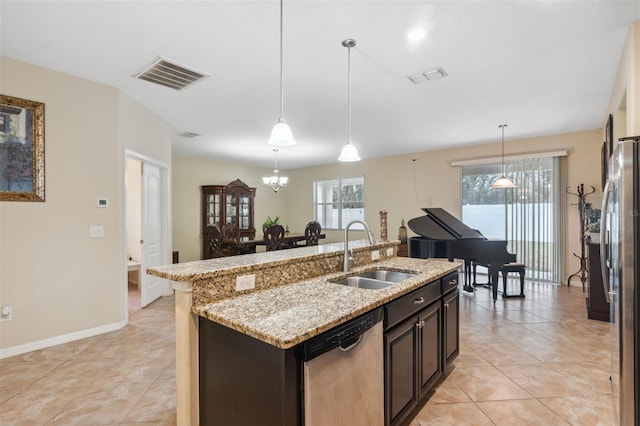 kitchen featuring sink, stainless steel appliances, light stone countertops, a center island with sink, and decorative light fixtures