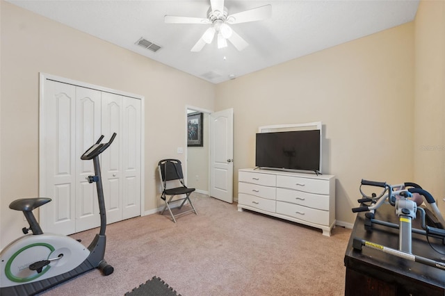 workout room with ceiling fan and light colored carpet