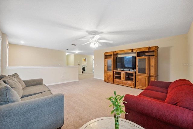 living room featuring washer / clothes dryer, light colored carpet, and ceiling fan