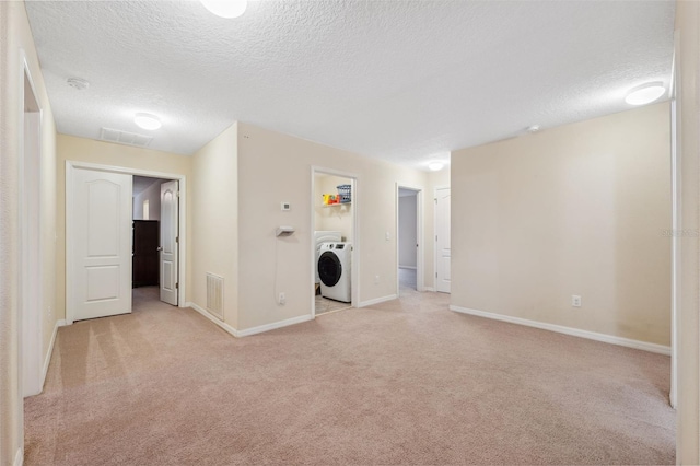 washroom with washer / clothes dryer, light colored carpet, and a textured ceiling