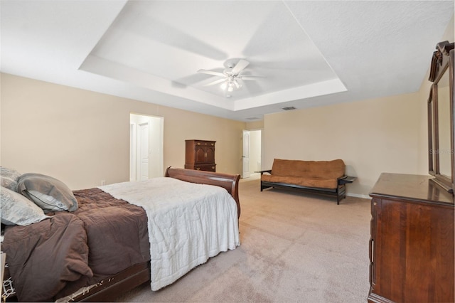 carpeted bedroom with ceiling fan and a raised ceiling