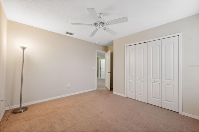 unfurnished bedroom featuring light colored carpet, a closet, and ceiling fan