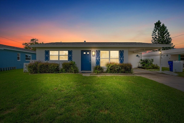 ranch-style home featuring a carport and a yard