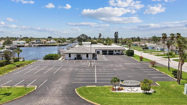 view of car parking featuring a water view and a lawn