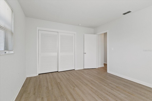 unfurnished bedroom featuring light hardwood / wood-style flooring and a closet