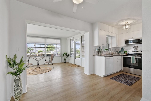 kitchen featuring stainless steel appliances, white cabinetry, tasteful backsplash, and light hardwood / wood-style floors