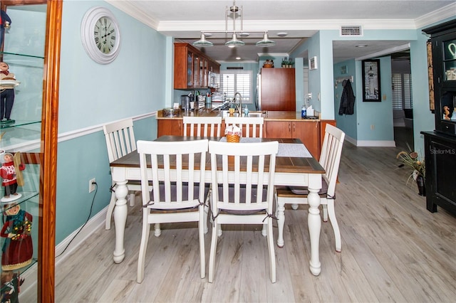 dining area featuring ornamental molding and light hardwood / wood-style flooring