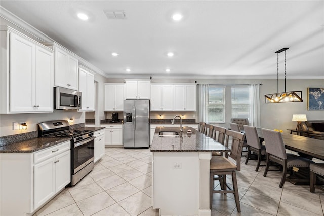 kitchen with ornamental molding, appliances with stainless steel finishes, sink, and a center island with sink