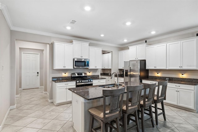 kitchen with an island with sink, sink, white cabinets, a kitchen bar, and stainless steel appliances