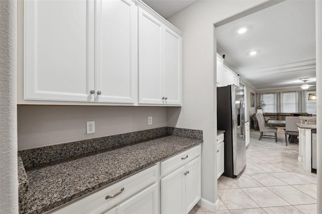 kitchen featuring white cabinets, light tile patterned floors, stainless steel fridge, and dark stone counters