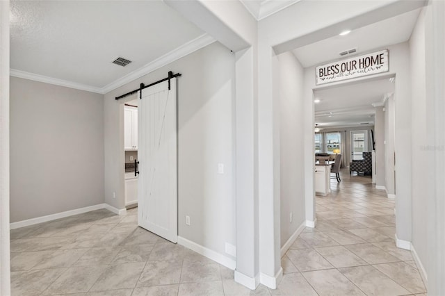 corridor with ornamental molding, a barn door, and light tile patterned floors