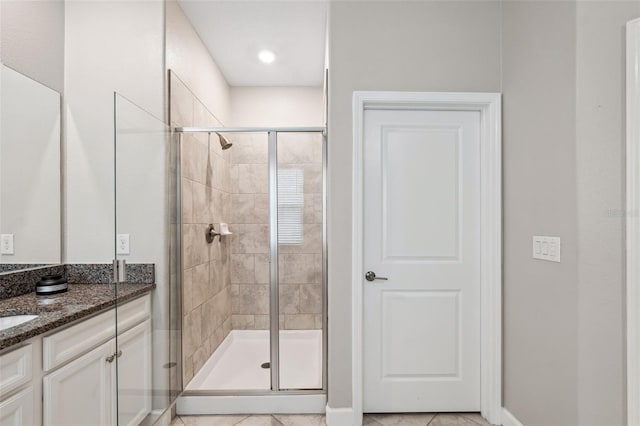 bathroom with walk in shower, vanity, and tile patterned flooring