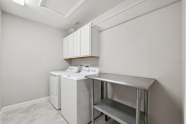 washroom featuring light tile patterned flooring, cabinets, a textured ceiling, and washing machine and clothes dryer