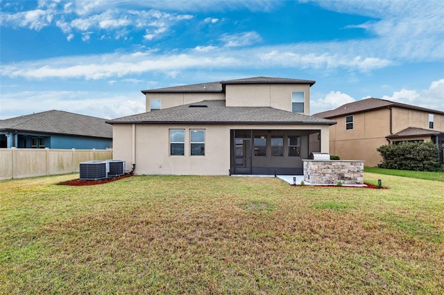 rear view of house featuring central AC unit, a sunroom, and a lawn