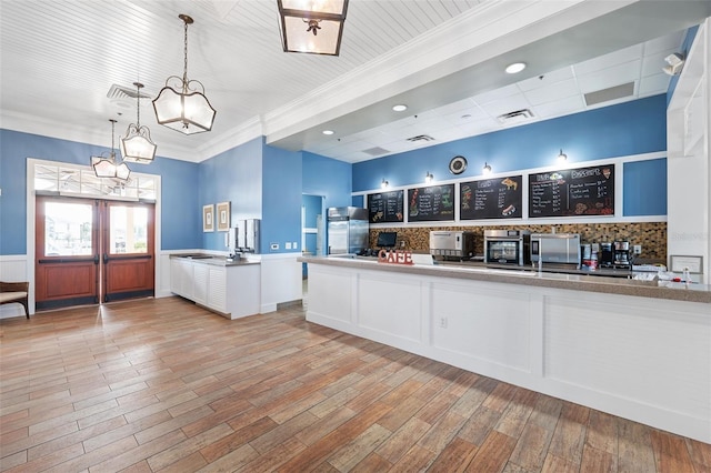 kitchen featuring crown molding, decorative light fixtures, and light hardwood / wood-style flooring