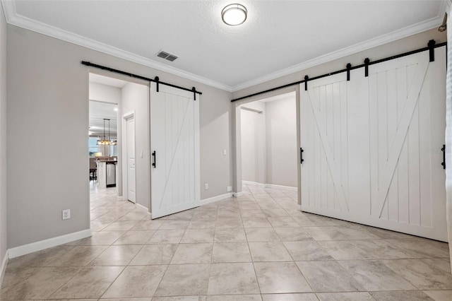 tiled empty room with ornamental molding, a barn door, and a textured ceiling