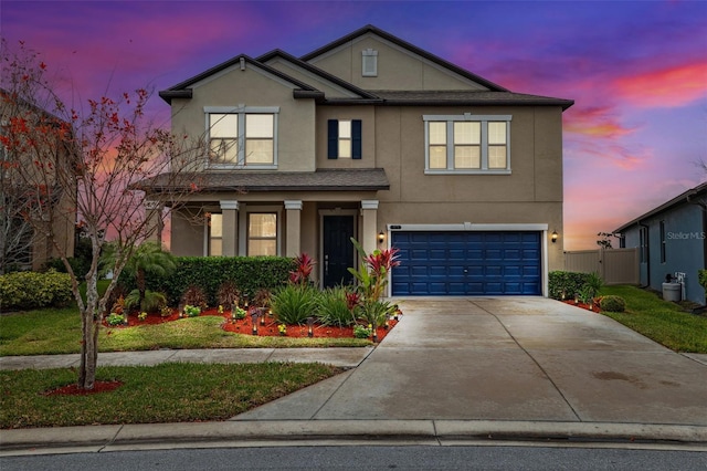 traditional-style home featuring concrete driveway, an attached garage, fence, and stucco siding