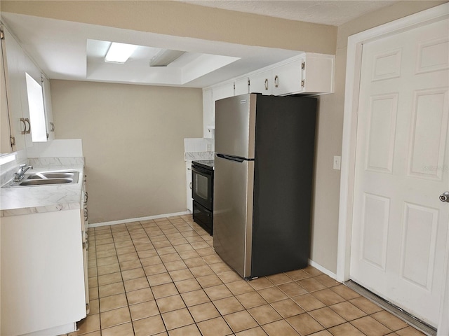 kitchen featuring sink, stainless steel fridge, white cabinetry, black range with electric stovetop, and a tray ceiling