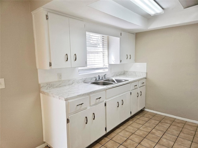 kitchen featuring light tile patterned floors, sink, and white cabinets