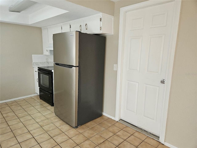 kitchen featuring light tile patterned flooring, black electric range oven, white cabinetry, a wood stove, and stainless steel fridge