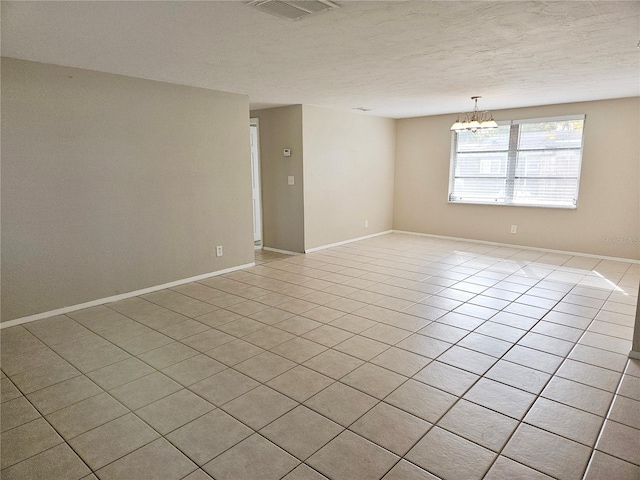 tiled empty room with a chandelier and a textured ceiling