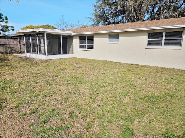 back of house featuring a sunroom and a lawn