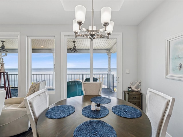 dining space featuring a chandelier and a water view