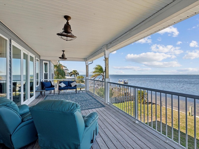 wooden terrace with an outdoor living space, a water view, and a yard