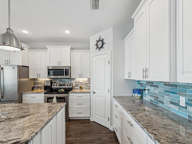 kitchen with appliances with stainless steel finishes, hanging light fixtures, and white cabinets