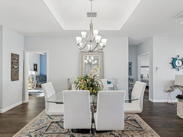 dining space with dark hardwood / wood-style floors and an inviting chandelier