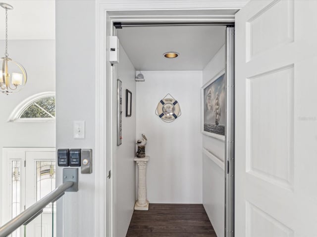 hall with a notable chandelier and dark hardwood / wood-style floors