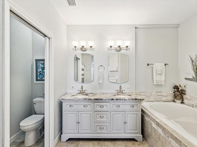 bathroom featuring vanity, tiled bath, and toilet