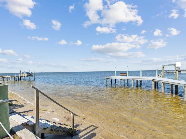 view of dock featuring a beach view and a water view